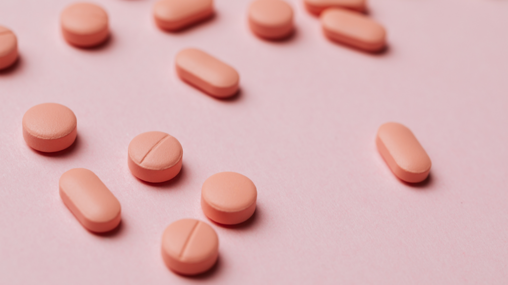 Pink supplement pills on a pink background