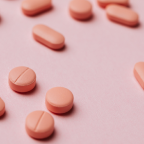 Pink supplement pills on a pink background